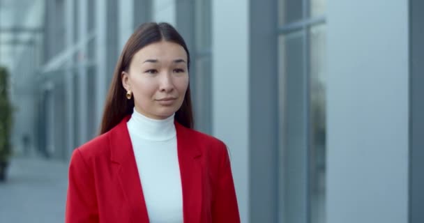 Beskär utsikt över affärskvinna tittar åt sidan när du går på gatan nära kontorsbyggnad. Asiatisk elegant kvinna ler när du promenerar i affärsområdet. Begreppet framgångsrika människor. — Stockvideo