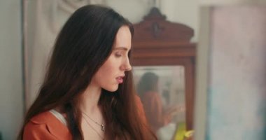 Güzel bir kadının sanat atölyesinde dikilirken başyapıt yaratmasına yakından bakın. Resmine bakarken fırça ve palet tutan ilham verici kadın ressamın portresi.