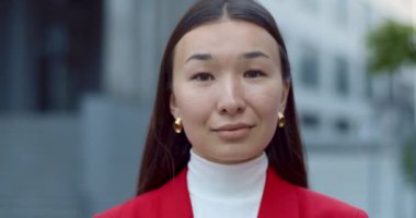 Çekici Asyalı bir kadının kameraya bakıp poz verişini yakından izleyin. Sokakta ayakta gülümseyen başarılı iş kadınının portresi. Vesikalık fotoğraf kavramı.