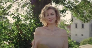 Parkta yürüyen şapkalı güzel bir genç kadın manzarası. Kameraya bakan kısa sarı dalgalı saçlı çekici kadın portresi. Yaşam tarzı kavramı. Rüzgarlı hava.