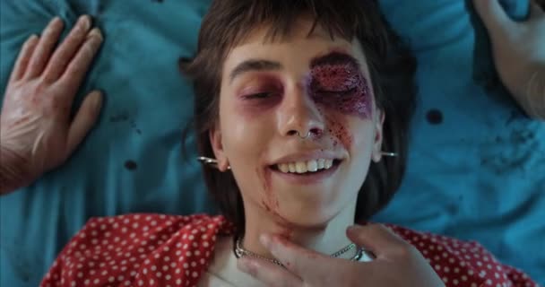Kan ve kafa yaralanması geçiren hippi kız hastane sedyesinde yatarken gülümsüyor. Ciddi travmaları olan, ambulansla giden bin yıllık bir kadının yakın görüntüsü. Sağlık hizmetleri kavramı. — Stok video