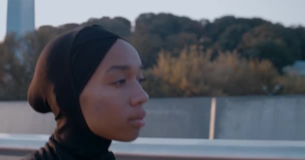 Крупним планом бачить молоду мусульманку, що біжить на мосту. Вид збоку на жінку в хіджабі. Концепція здорового способу життя. На відкритому повітрі . — стокове відео