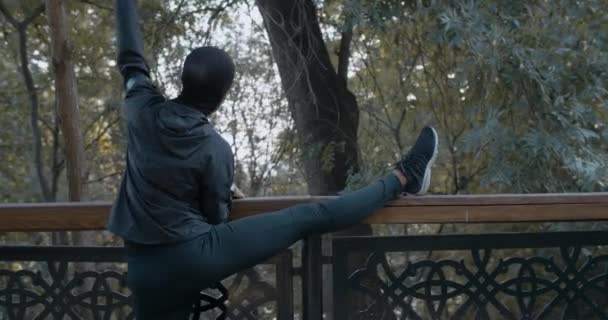 Rückansicht einer Afroamerikanerin beim Aufwärmen vor dem Sport auf der Straße. Weibliche Person im Hidschab, die sich im Freien streckt. Konzept eines gesunden Lebensstils, Sport. — Stockvideo