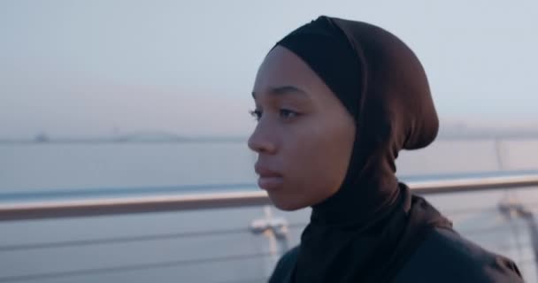 Close-up zicht op mooie moslim vrouw rennend op de brug. Zijaanzicht van jonge vrouwelijke persoon in hijab joggen. Concept van een gezonde levensstijl. Buiten. — Stockvideo