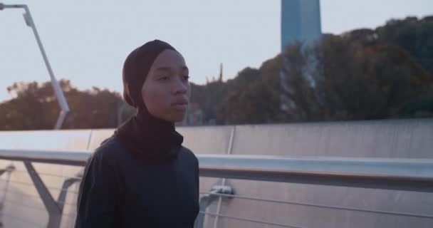 Vista del raccolto di una giovane donna musulmana che corre sul ponte. Vista laterale della persona femminile in hijab va a fare jogging. Concetto di stile di vita sano. All'aperto. — Video Stock