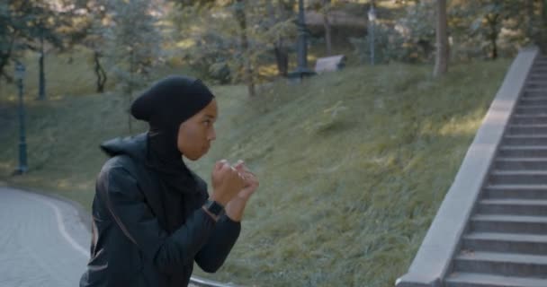 Close up view of young concentrated muslim woman in sports suit boxing alone. Female person in hijab doing self training while standing in park. Concept of healthy lifestyle, sport. — Stock Video