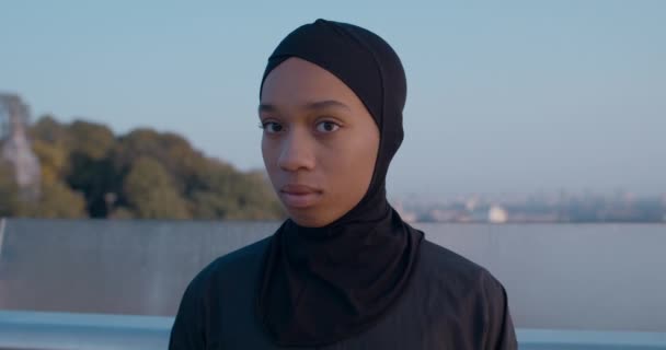 Nahaufnahme einer attraktiven muslimischen Frau, die den Kopf dreht und in die Kamera blickt. Porträt einer jungen Frau im Hidschab, die auf der Straße posiert. Konzept des Lebensstils. Draußen. — Stockvideo