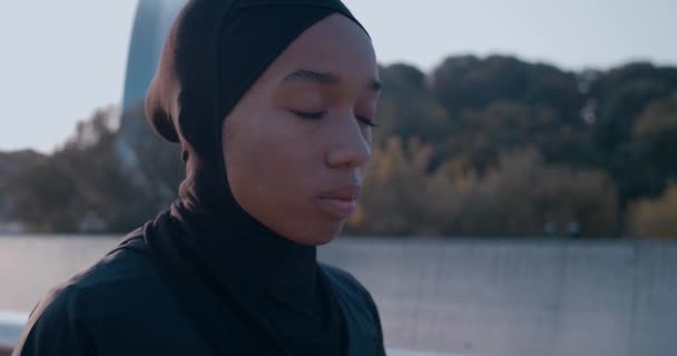 Bekijk van dichtbij de moslimvrouw die diep ademt terwijl ze op straat staat. Jonge vrouw in hijab vangt haar adem na het rennen. Concept van levensstijl, sport. Buiten. — Stockvideo