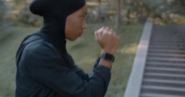 Junge, konzentrierte Muslimin im Sportanzug-Boxen allein. Afroamerikanerin im Hidschab beim Selbsttraining im Park. Konzept eines gesunden Lebensstils, Sport. — Stockvideo