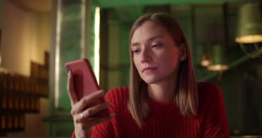 İnternette gezinirken ve gülümserken güzel genç bir kadının ekranını kapat. Akıllı telefon kullanan ve barda otururken gülümseyen mutlu bir kadın. Duyguların kavramı.