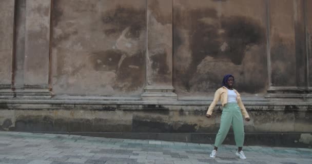 古い街の通りで踊る幸せな魅力的な女性ダンサー。屋外で動きをしながらカメラを探している若い女性ダンサー。良い気分、現代的なライフスタイルの概念. — ストック動画