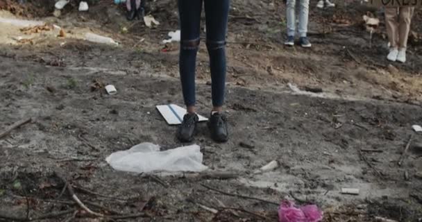 Grupo de personas diversas sosteniendo carteles de cartón con consignas mientras están de pie en el bosque lleno de basura. Activistas ecologistas atacan contaminación ambiental y destrucción de la naturaleza. — Vídeo de stock