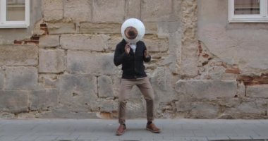 Büyük göz maskesi takan Afro-Amerikalı adam Old City Caddesi 'nde dans ediyor. Moda kıyafetleri içinde bir adam taşınıyor ve eğleniyor. İyi ruh hali kavramı, olumlu duygular..