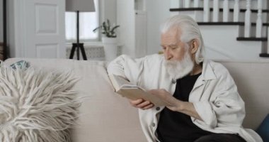 Yaşlı gri saçlı adamın okuma yazması ve boş zaman geçirmesi. Sakallı emekli erkek, rahat evdeki kanepede otururken kitap açıyor. Emeklilik kavramı, insanlar ve duygular.