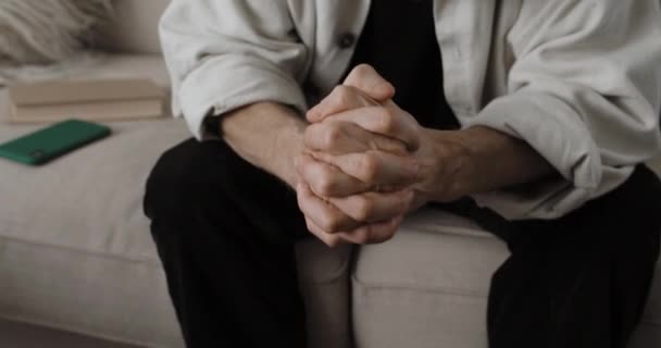 Crop Ansicht alter männlicher Person in Depressionen sitzt auf dem Sofa. Männlicher Rentner legt Hände zusammen. Konzept der Rentnerprobleme. — Stockvideo