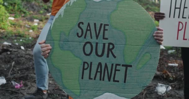 Schnittansicht von Menschen Hände halten Karton Erde Modell mit speichern unseren Planeten schriftlich. Umweltaktivist steht in einer Gruppe von Menschen in einem Wald voller Müll. Konzept der Naturzerstörung. — Stockvideo