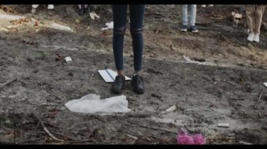 Afro-Amerikan kadın tabelası ile en alttan en üste. Geleceğimizi aktivistler grubunun önünde çöpe atma. Afişleri ve sloganları olan insanlar çöplerle dolu bir parkta kameraya bakıyorlar..