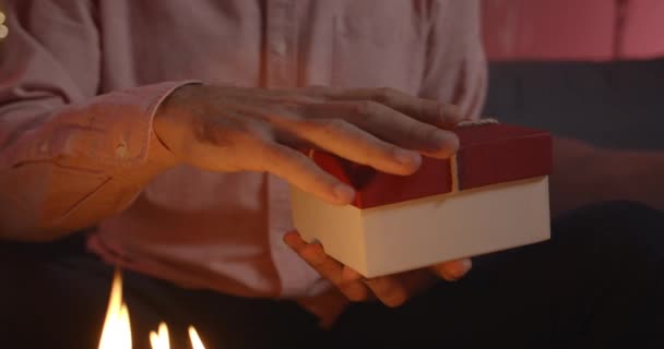 Oříznout pohled na muže držícího krabici na kolenou. Dort se svíčkami u něj. Koncept narozeninové oslavy. — Stock video