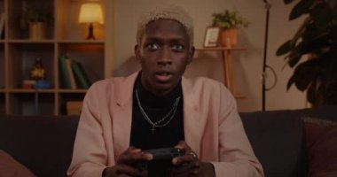 Joy 'un elinde joystick tutan ve kullanan genç adamın yakın görüntüsü. Kanepede rahatça otururken Afrika kökenli Amerikalı bir erkek oyun oynuyor. Boş zaman ve eğlence anlayışı.