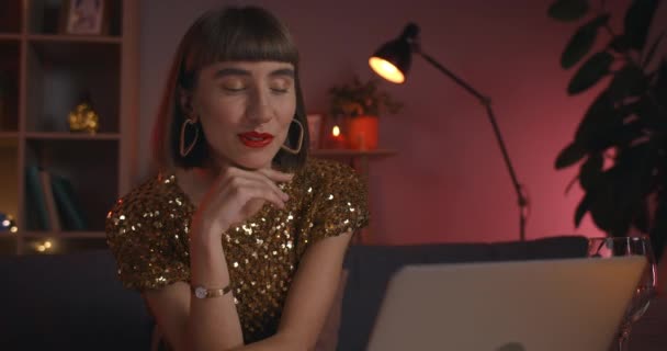 Çevrimiçi sohbet ederken çekici bir kadının konuşmasını yakından izle. Evde dizüstü bilgisayara bakarken gülümseyen ve el sallayan şık bir kadın. Çevrimiçi tarih kavramı. — Stok video