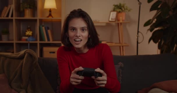 Crop view van opgewonden vrouw houden en met behulp van joystick tijdens het zitten op de bank. Millennial vrouwelijke persoon spelen spel terwijl het hebben van goede tijd. Begrip vrijetijdsbesteding en entertainment. — Stockvideo