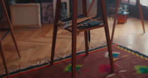 2020年1月17日:女性が手を取りながら、イーゼル棚の上に横たわる画家の絵筆のビューを閉じます。中に入って。創造性と美術品の概念. — ストック動画