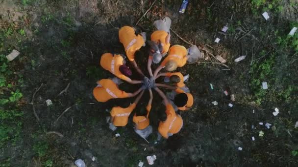 Vue aérienne du dessus des gens en gants mettant les mains ensemble et applaudissant. Des éco-activistes se répandent dans la forêt et ramassent des déchets. Concept de travail d'équipe, pollution de la nature. — Video