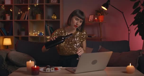 Widok na zboże atrakcyjne millenium kobieta mówi i wylewa wino do szkła, patrząc na ekranie laptopowym.Pozytywny kobieta osoba w stylowych ubrań komunikujących się online w domu. — Wideo stockowe