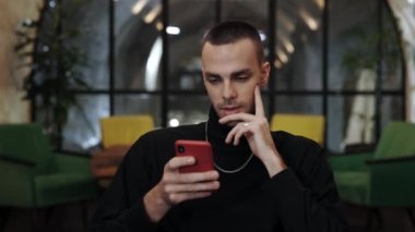 Kafede akıllı telefon kullanırken tüylü beyaz adamın hayret verici bakışları ve 