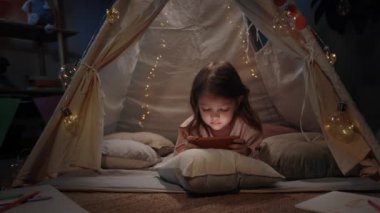 Güzel derme çatma kulübede akşam evde oyun oynayan sevimli bir kız. Akıllı telefon kullanırken yerde yatan tatlı küçük çocuk. Boş zaman ve dikkatsiz çocukluk kavramı.