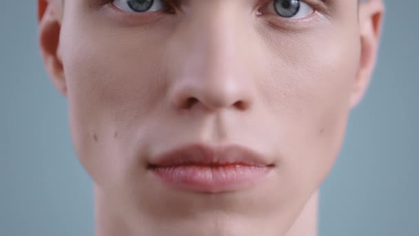 Вид на урожай красивого молодого человека, открывающего глаза и смотрящего в камеру. Портрет мужской модели со светло-голубыми глазами на фоне студии. — стоковое видео