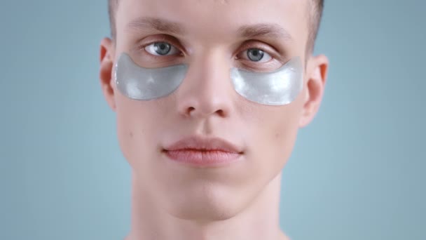カメラを探して目のパッチの下で若い男の作物ビュー。ライトブルーの目をポーズで男性ハンサムなモデルの肖像画。肌や顔のケアの概念. — ストック動画