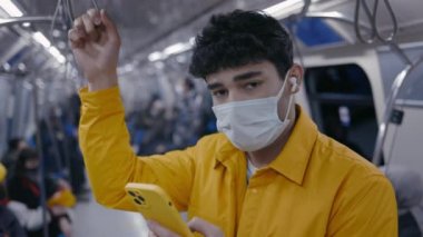 Hareket halindeki metroda akıllı telefon kullanan maskeli adam.