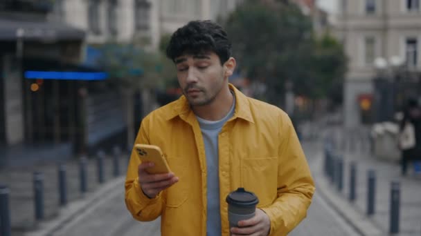 Jonge hipster met smartphone en koffie drinken op straat — Stockvideo