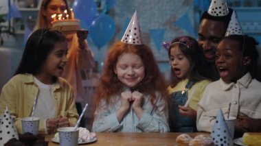 Önüne doğum günü pastası getirip koyarken uzun kızıl saçlı küçük bir çocuğun gözleri kapalı beklediği ekin manzarası. Pastaya mum üfleyen ve parti yapan kız..