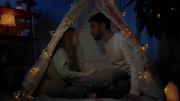 즐거운 아버지와 십 대 소녀가 임시 오두막에 앉아 함께 즐거운 시간을 보내며 미소짓고 있다. 가족 시간에 대한 개념. — 비디오