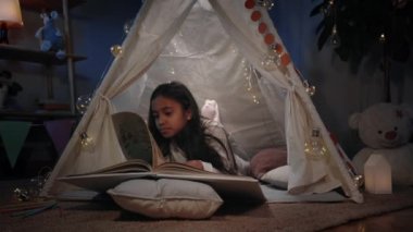 Akşamları sevimli dekoratif çadırda siyah uzun saçlı sevimli bir kız sayfaları çeviriyor. İlginç bir kitap okurken yerde yatan güzel bir genç. Boş zaman kavramı..