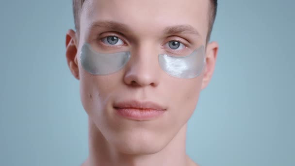 Imagen del hombre milenario con parches bajo los ojos mirando a la cámara. Retrato de modelo guapo masculino con ojos azules claros posando. Concepto de cuidado de la piel y la cara. — Vídeo de stock