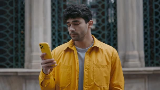 穿着黄色夹克站在街上用手机的男人 — 图库视频影像
