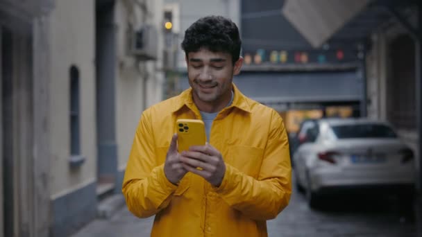 길을 걷고 현대의 스마트폰을 사용하는 미소짓는 사람 — 비디오