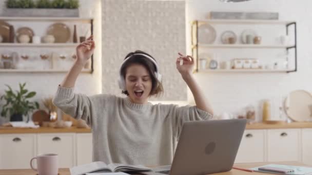 Femme joyeuse dans les écouteurs se reposant pendant l'éducation en ligne — Video