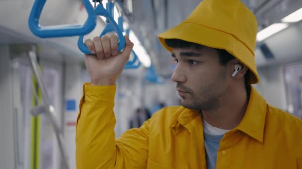 Sonriente hombre escuchando música en auriculares inalámbricos en el metro — Vídeos de Stock