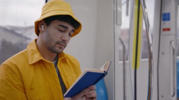 Стильний чоловік читає книгу під час їзди в метро — стокове відео