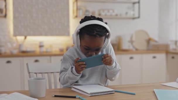 Menina da escola alegre jogando jogos no smartphone — Vídeo de Stock