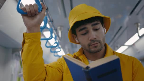 Pasajero masculino en auriculares leyendo libro en metro — Vídeo de stock