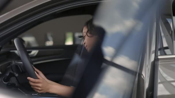 Atractiva mujer africana probando coche nuevo en concesionario — Vídeos de Stock