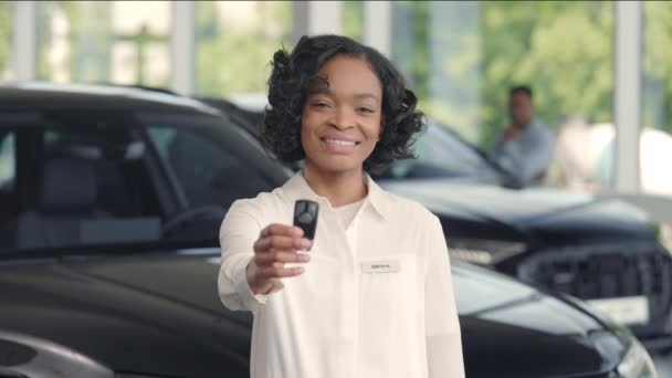 Distribuidor femenino posando en salón de coches con llaves en las manos — Vídeos de Stock