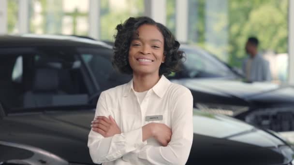 Afrikanischer Autohändler lächelt und posiert im Autosalon — Stockvideo