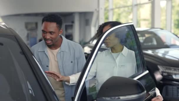 Femme concessionnaire présentant voiture de luxe pour le client masculin — Video