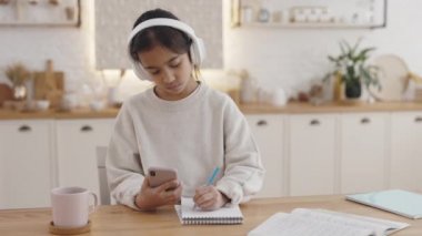Hintli öğrenci eğitim için kulaklık ve akıllı telefon kullanıyor.